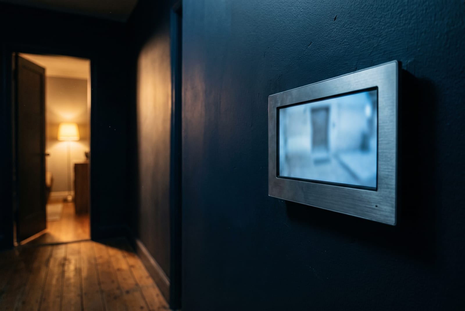 A video door station recording a visitor at a building entrance at night, lit by white light rather than infrared